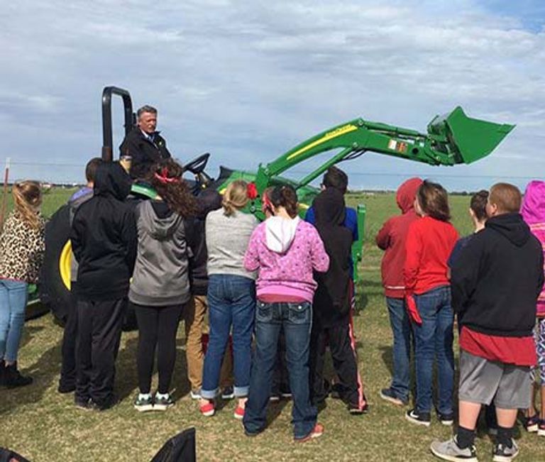 Man sitting in a tractor talking about safety to students